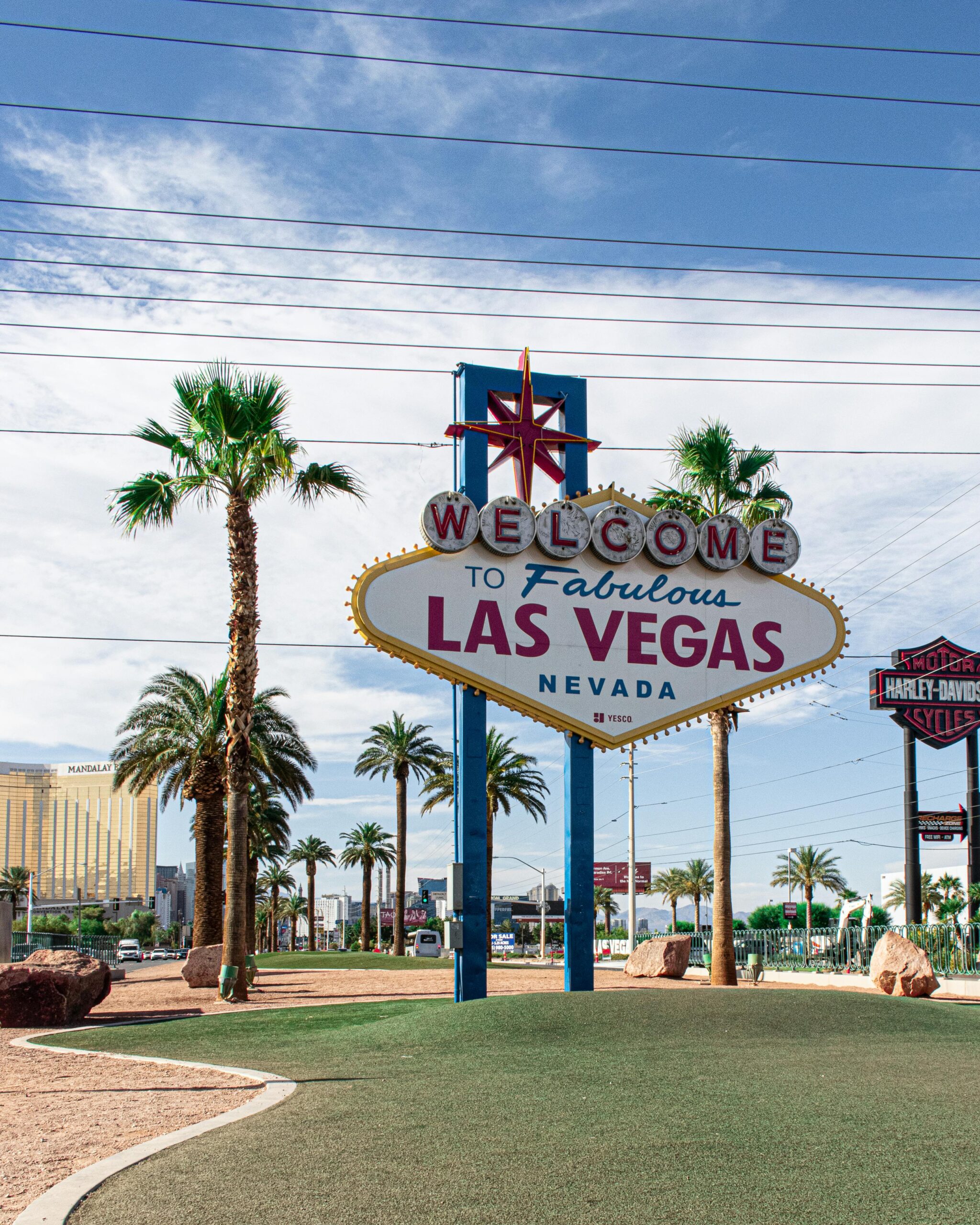 Home Famous Welcome to Las Vegas sign surrounded by palm trees on a sunny day.